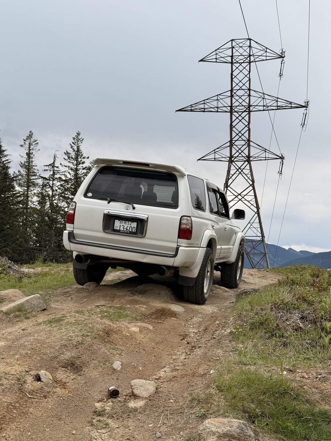 Rear of the Surf with its Japanese plate, parked under power lines on a ridge
