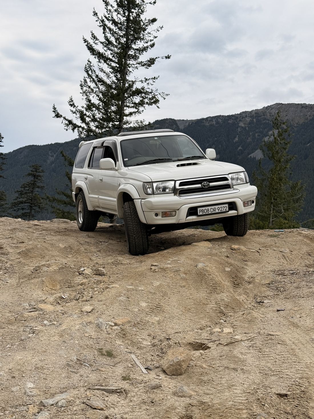 The Hilux Surf climbing a dirt mound on a mountain trail